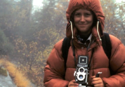 Eine Frau posiert in der Natur mit einer Vintage-Kamera.