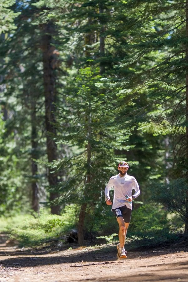 A man smiling and running along the Western States Endurance Run trail