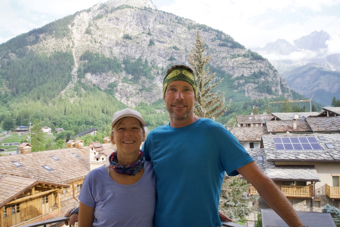A man and woman posing with housing structures and a mountain in the background
