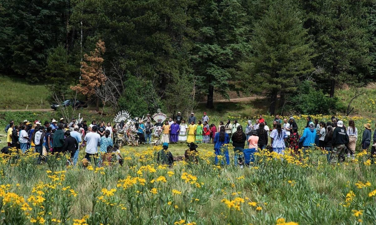 A group of people gathered in a open field for a cultural ceremony