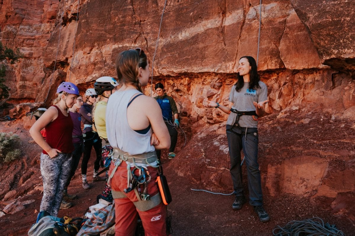A woman speaking to a group of rock climbing clinic participants 