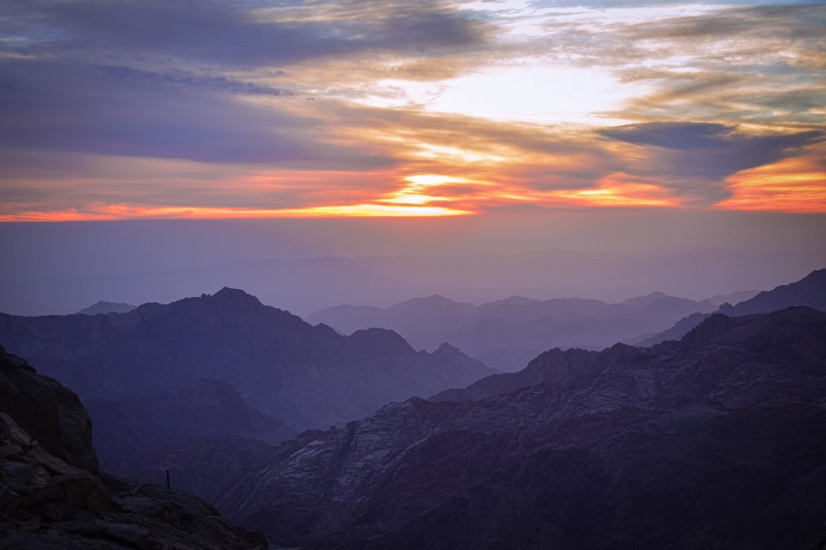 A landscape view of a mountain range during a cloudy sunset