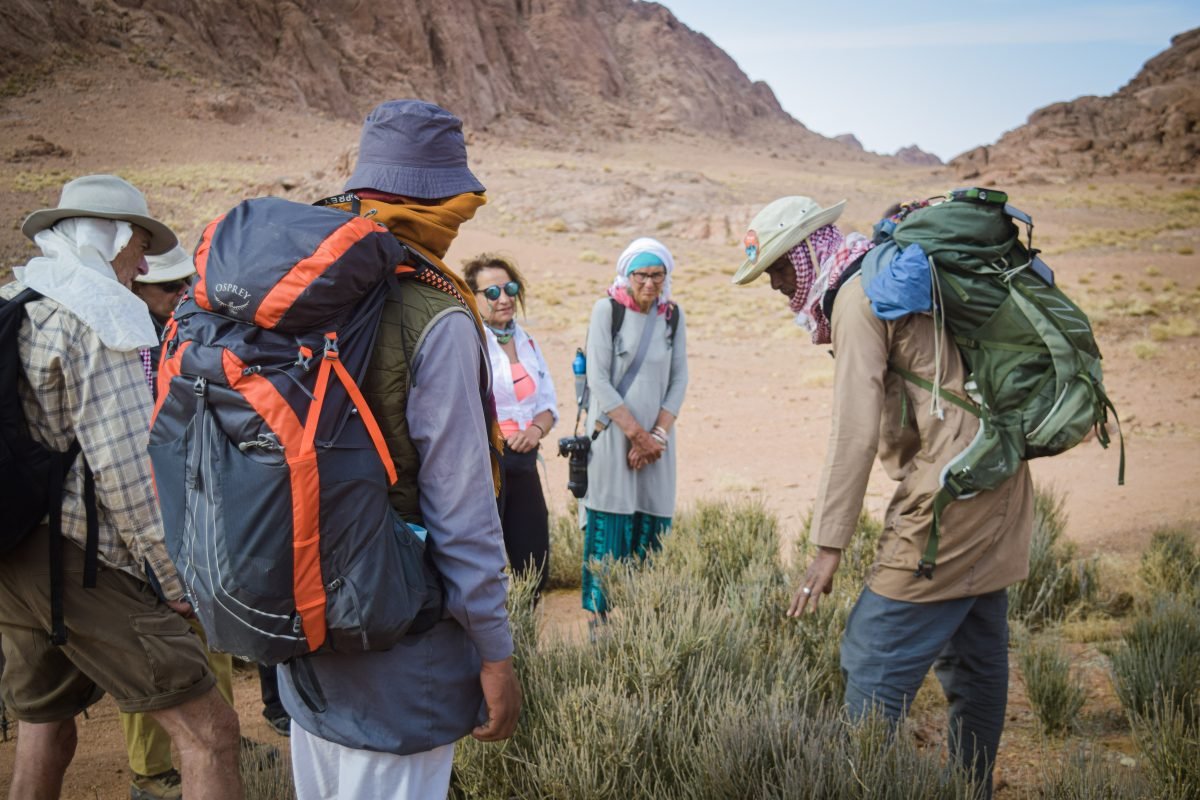 A group of people gathered in a circle along the trail, wearing backpacking gear