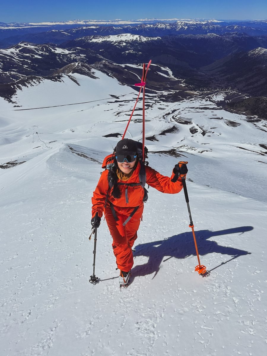 A woman in all orange touring up a mountain
