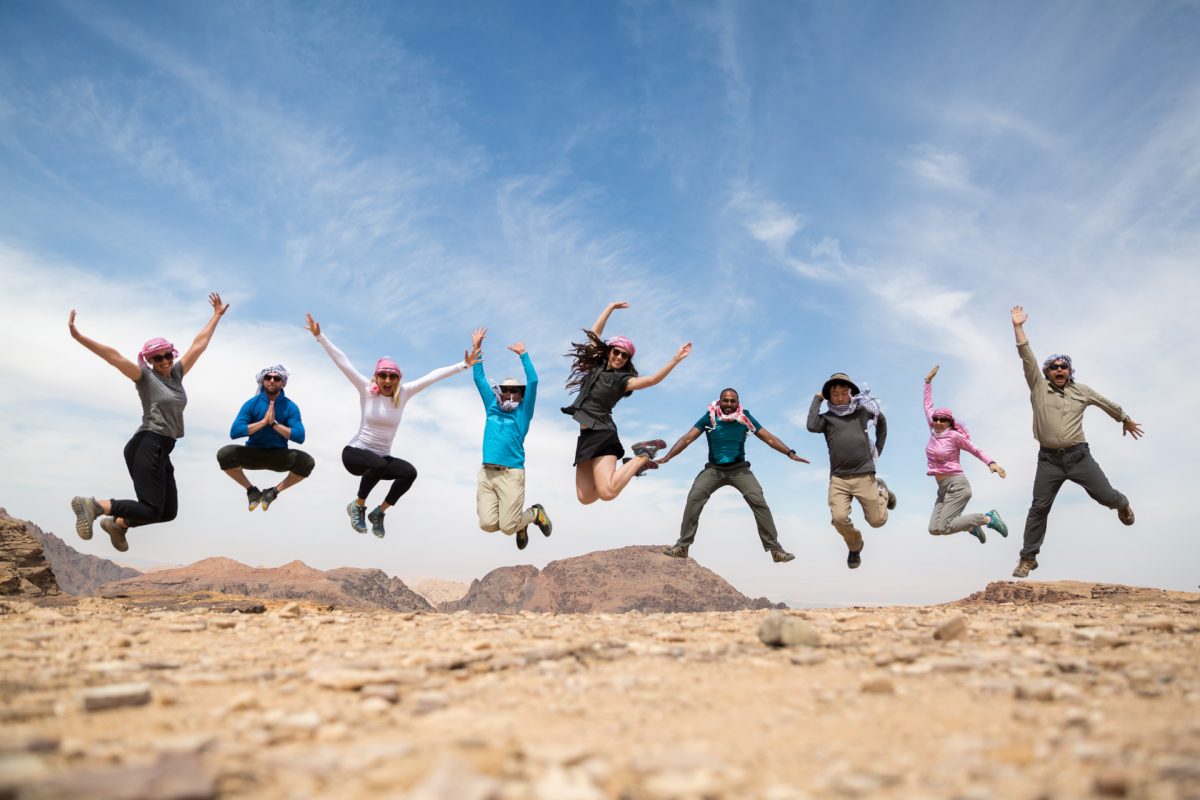 A group of people jumping and posing in all different way in the desert