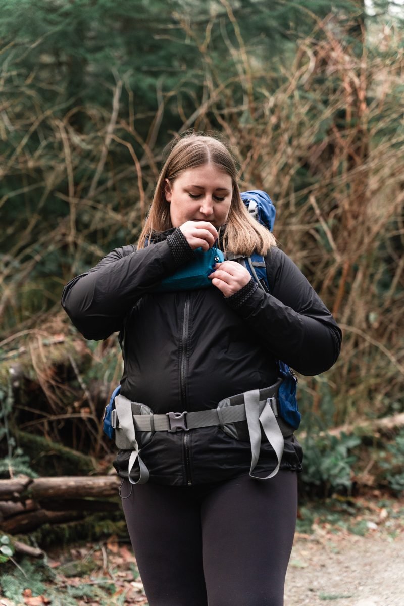 A woman accessing her pack pocket attached to her sternum strap on her backpack