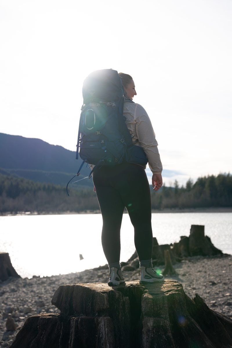 A woman standing near a lake in her backpacking gear