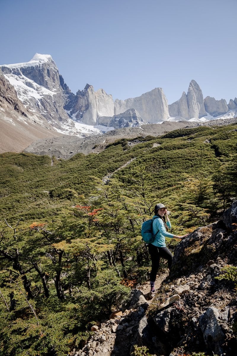 A woman in a teal shirt and a hat on trail in Patagonia