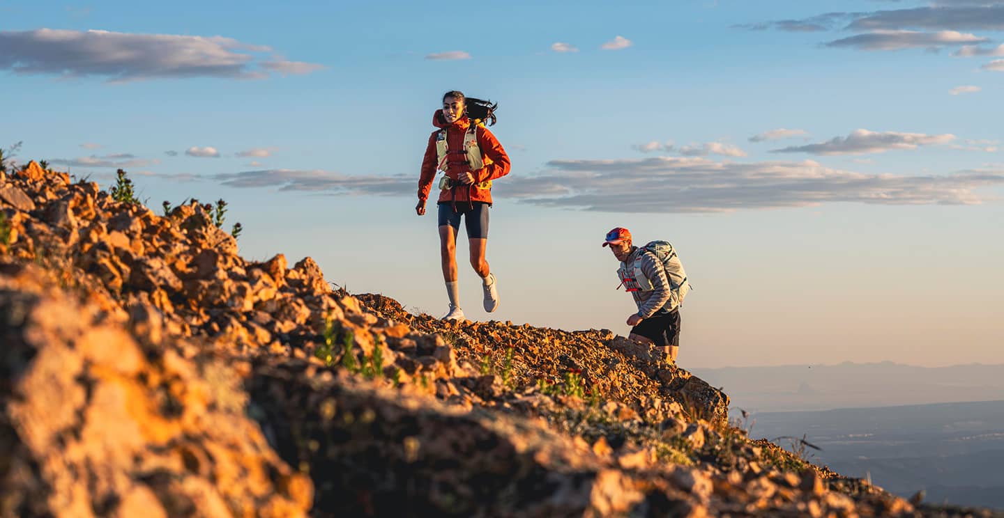 Trail runners wearing Talon and Tempest backpacks on a rocky ridgeline.